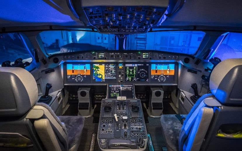 Modern airliner flight deck with large glass displays.